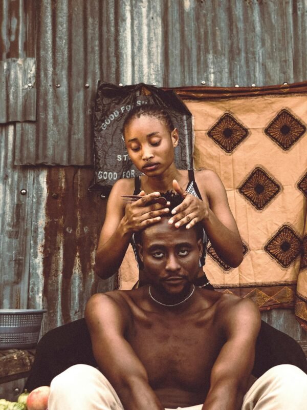 African woman combing man's hair, showcasing cultural intimacy and bonding.