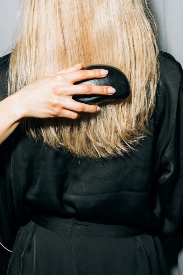 Close-up of a person brushing their long blonde hair in a relaxed setting.